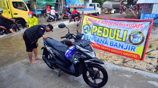 Relawan memperbaiki sepeda motor yang mogok akibat menerobos jalan yang tergenang banjir di jalan Desa Tanjung Karang, Jati, Kudus, Jawa Tengah, Rabu (04/01).