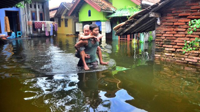 Warga melewati halaman rumah yang tergenang banjir di Dusun Gendok, Jati Wetan, Jati, Kudus, Jawa Tengah, Kamis (05/01)